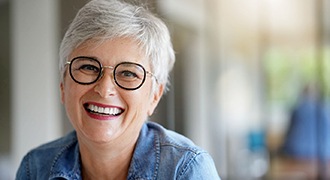 An older woman wearing glasses and smiling after receiving same-day crowns in Tyler
