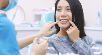 Woman pointing to smile in dental chair