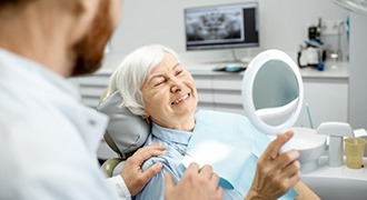 Woman admiring her new dentures in Tyler 