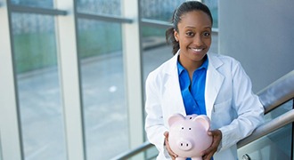 smiling dentist holding a piggy bank 