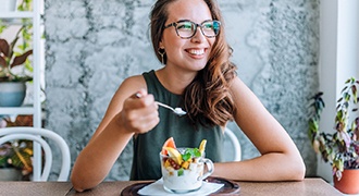 Woman smiling while eating healthy lunch at home
