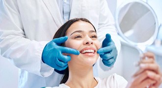 Woman smiling at reflection in handheld mirror