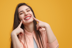 woman pointing to her beautiful smile from her cosmetic dentist in Tyler